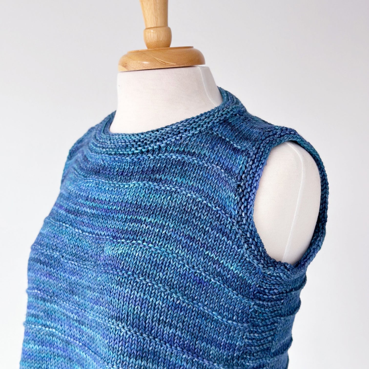 Crew neck sleeveless vest knit with tonal blue Malabrigo Rios on a dress form.