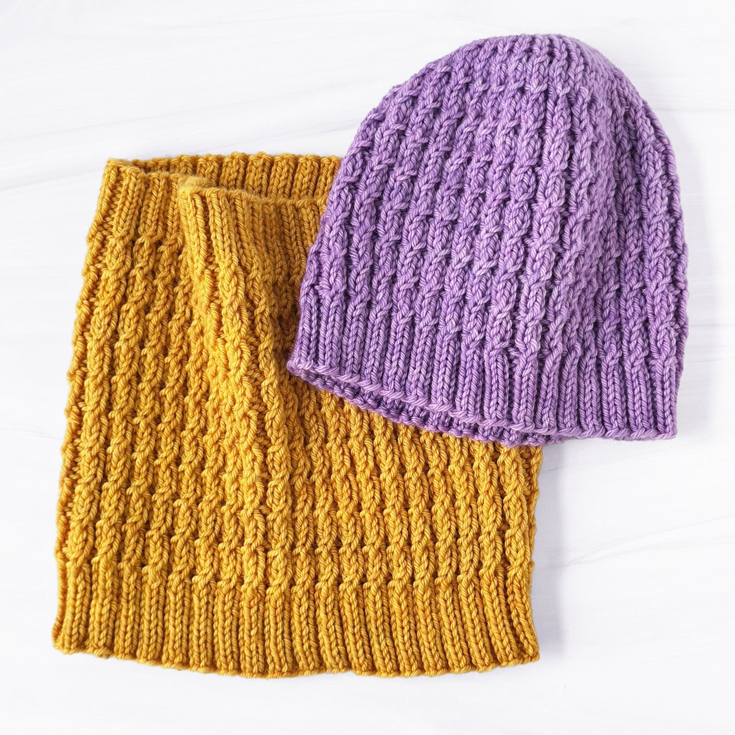 Baby Cable hat in light purple and cowl in gold.
