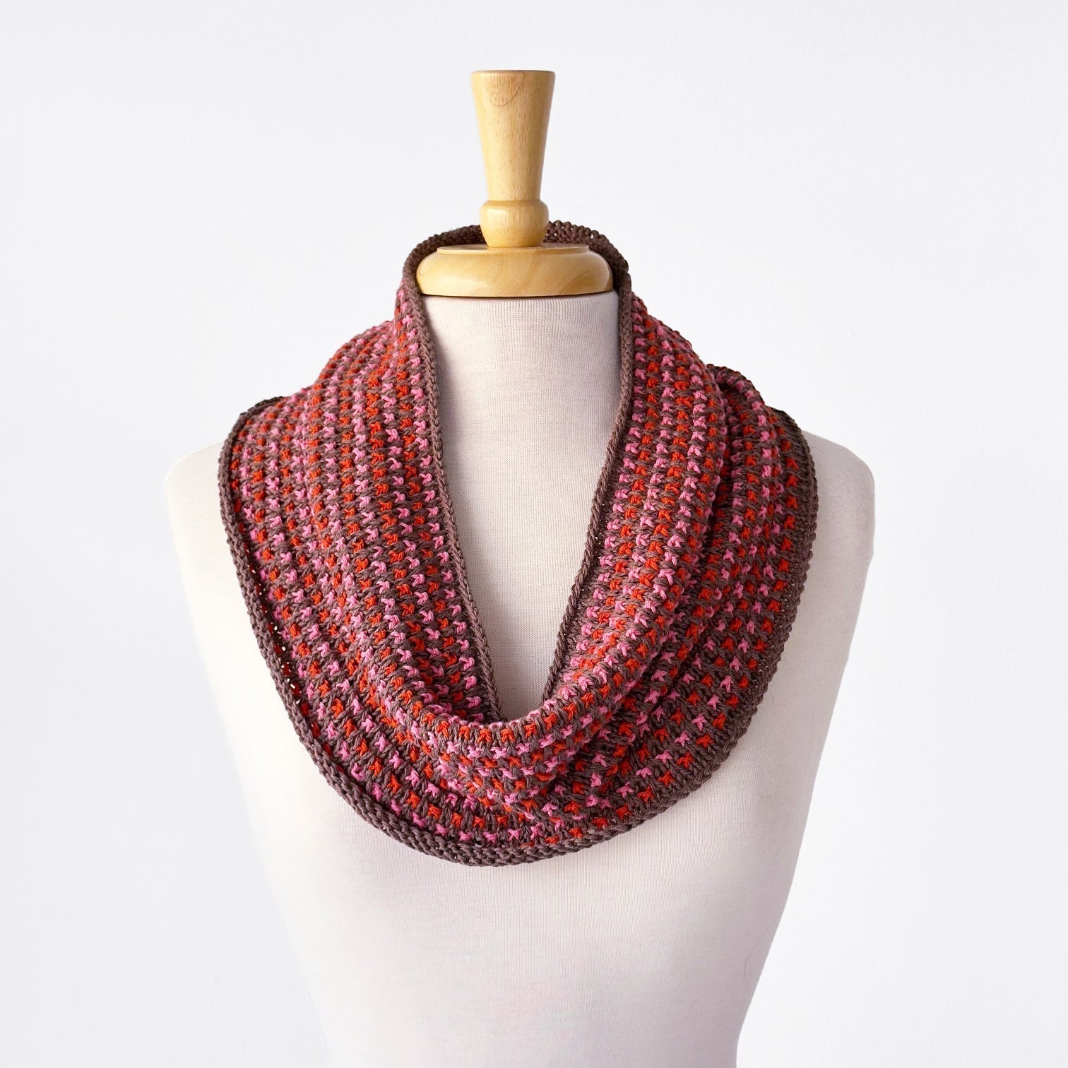 Tulip Cowl in Sandnes Garn Line in a warm brown, bright orange, and light pink.