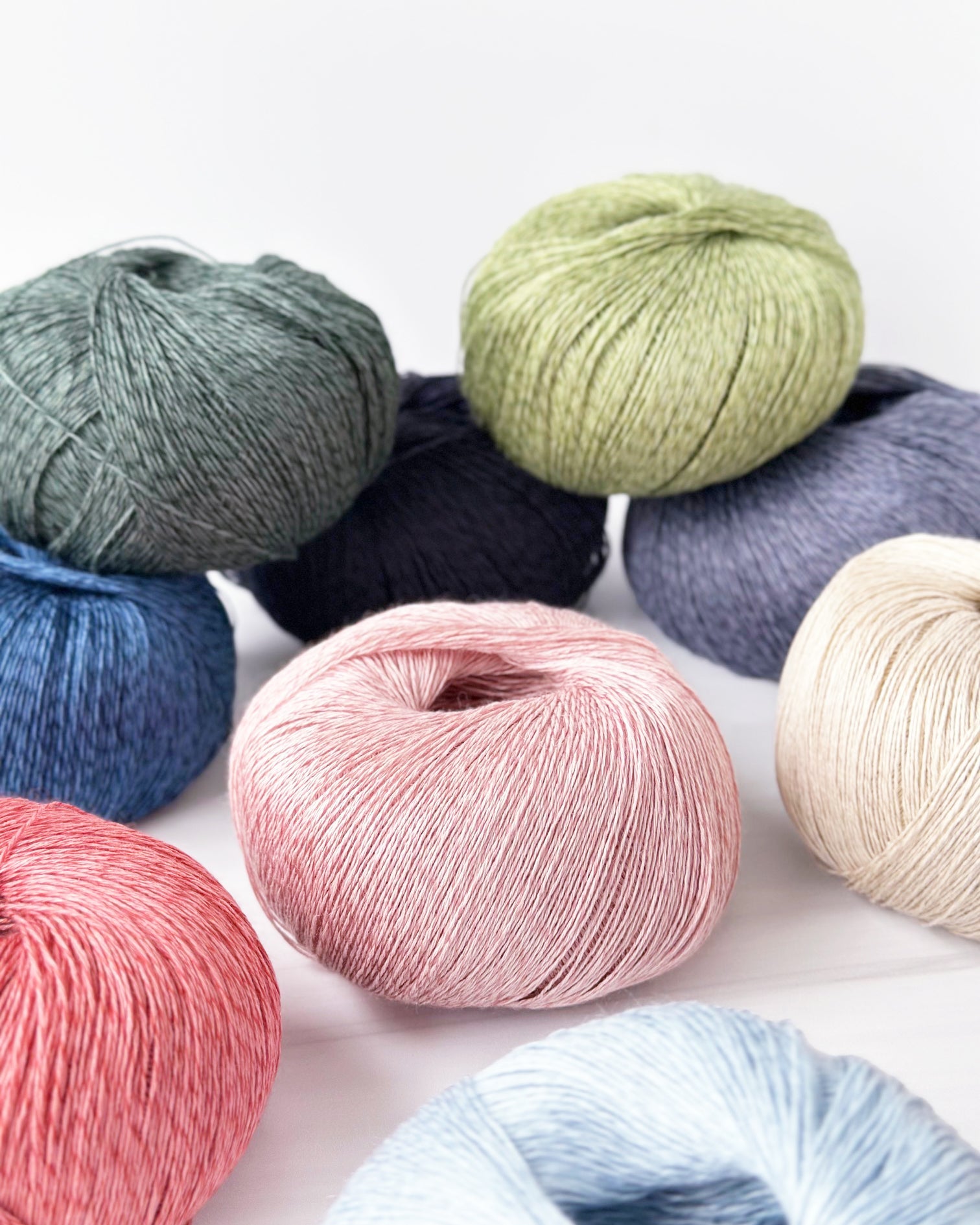 Several balls of Isager Trio 1 yarn in different shades.