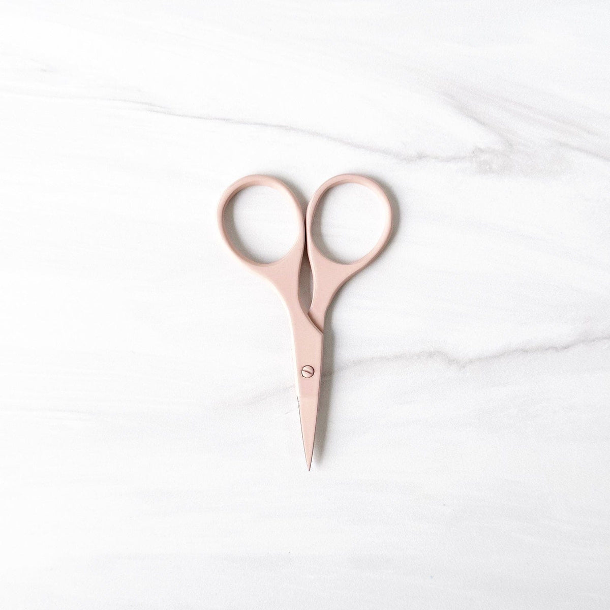 Blush pink scissors on white marble background