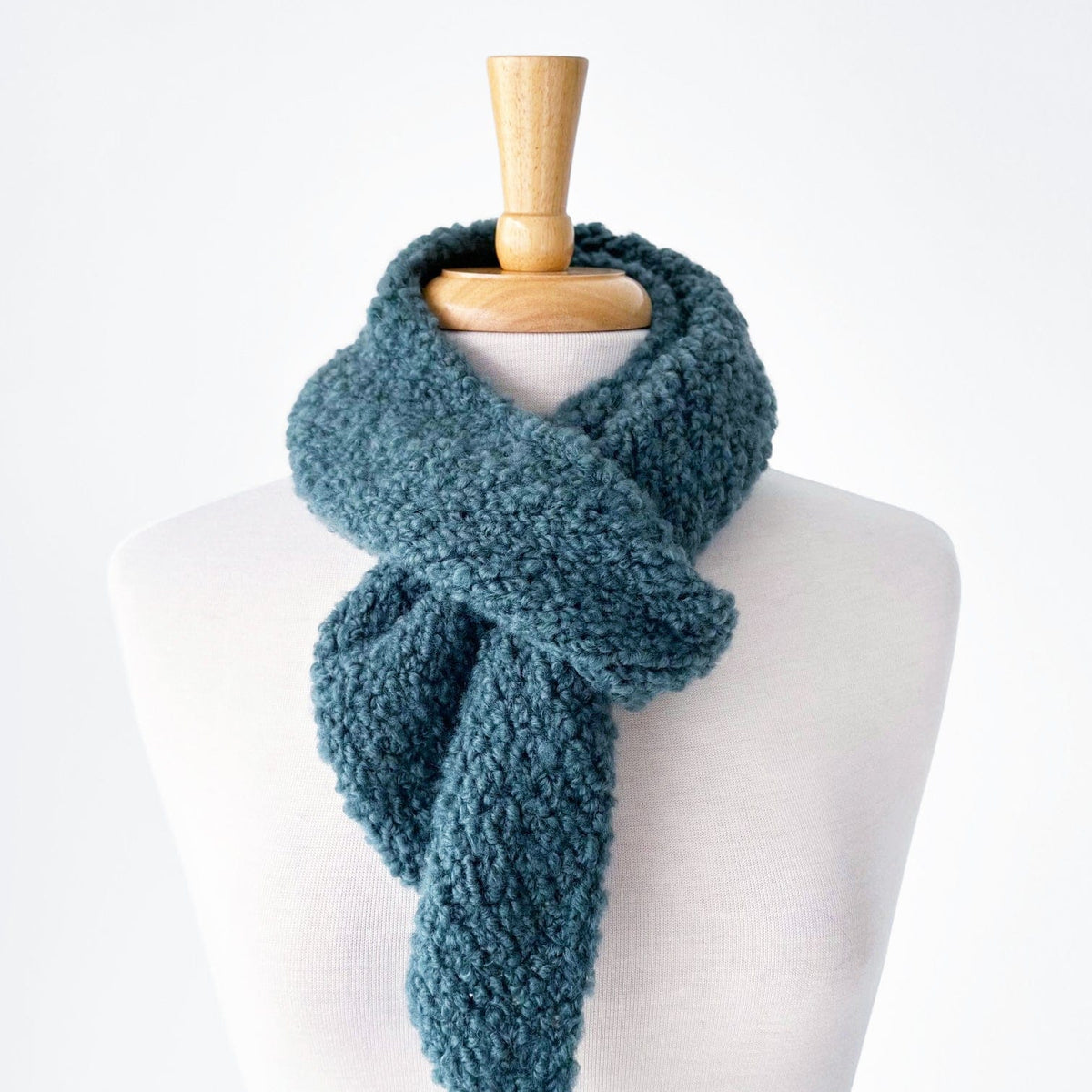 Bulky teal knit scarf on a mannequin