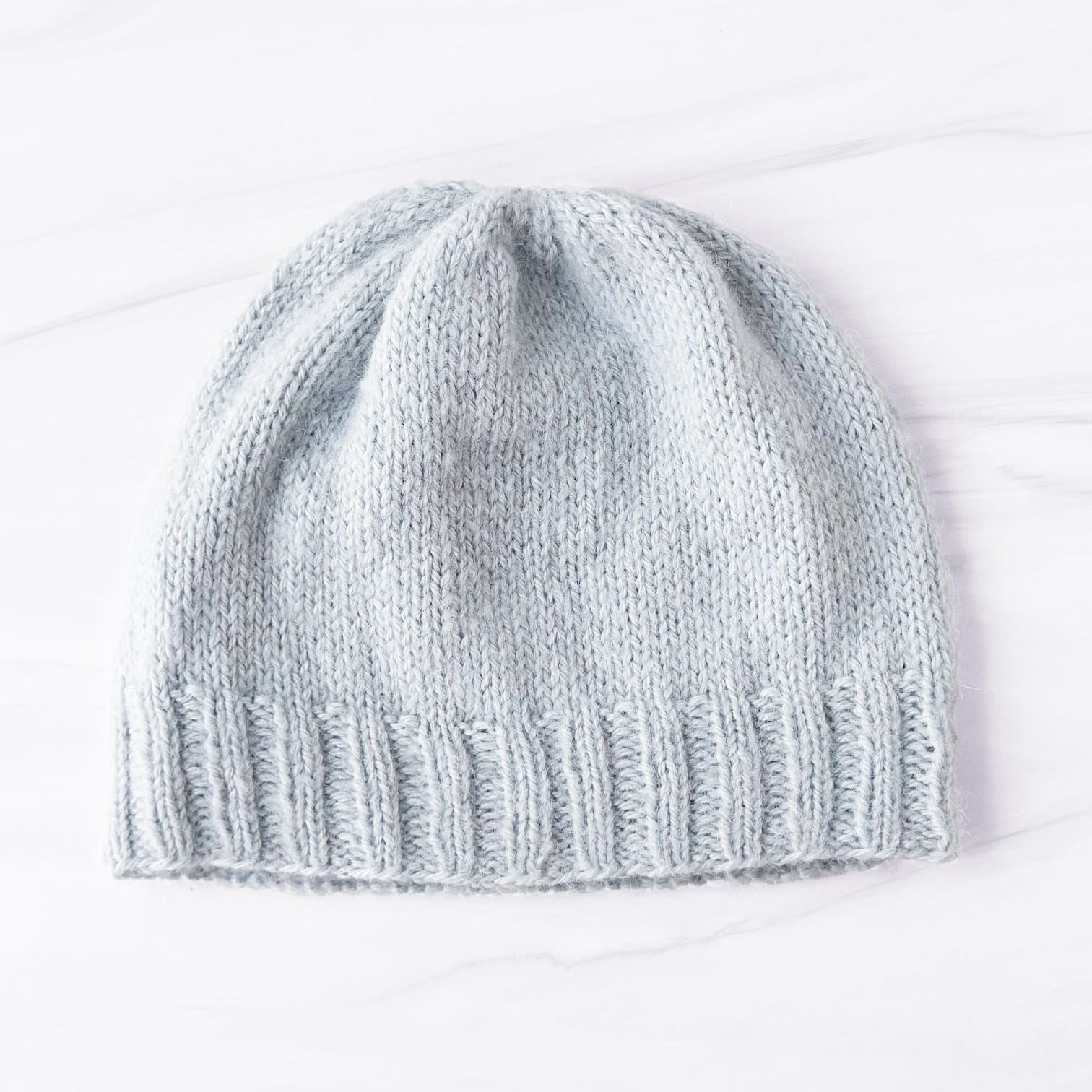 Knitted gray beanie on a white background