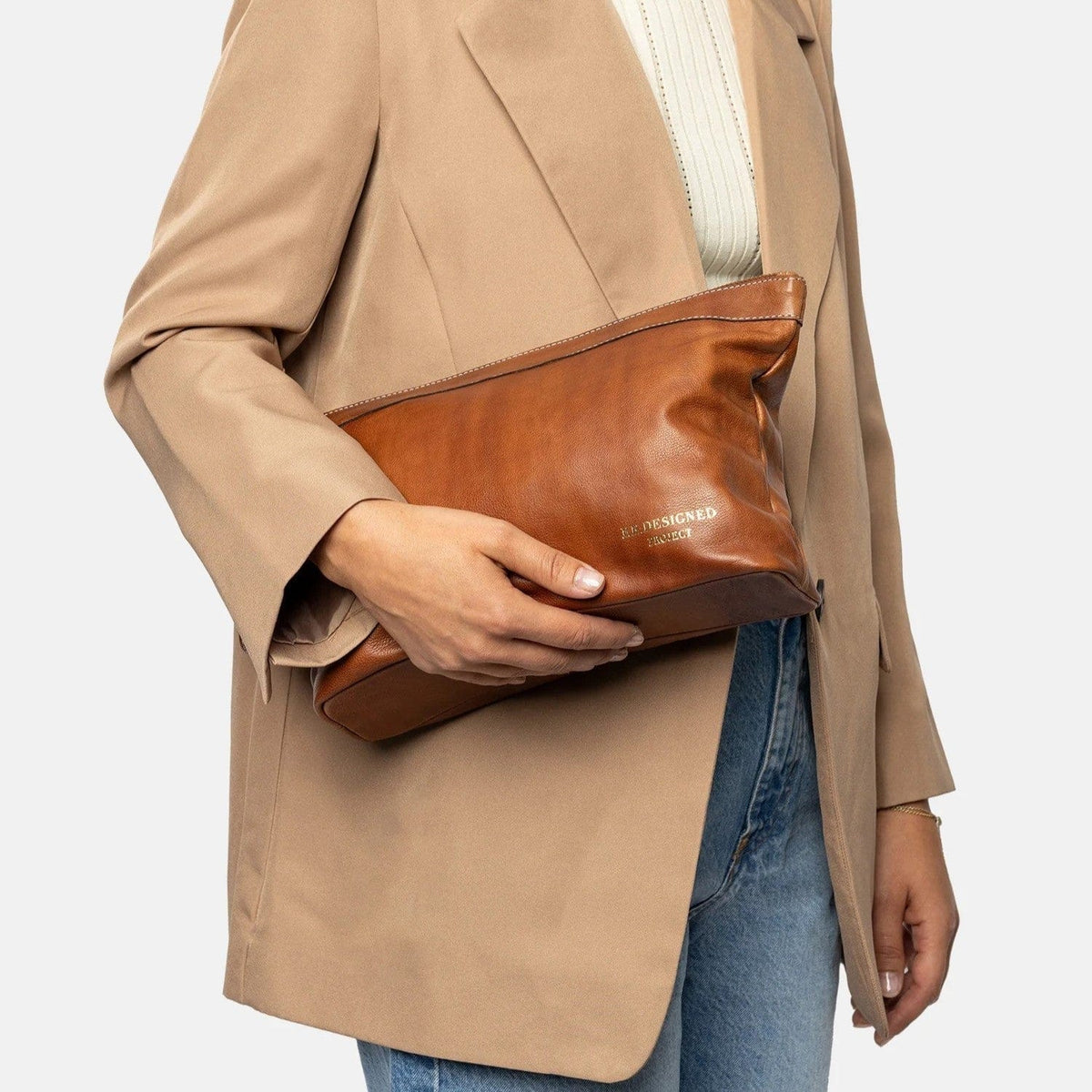 Woman holding brown leather clutch